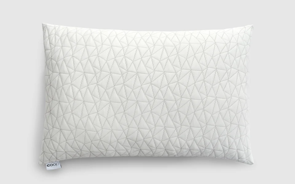 Coop Original Adjustable pillow, front view, quilted white cover with the coop tag on a light studio backdrop